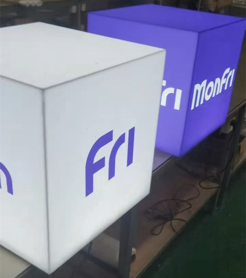 a white cube acrylic light box with purple "Mon" "Fri" logo and another purple cube acrylic light box with white "MonFri" logo